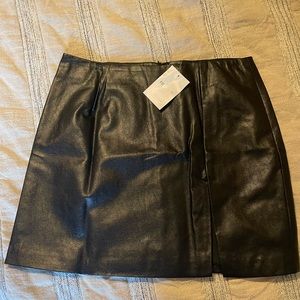 Black feaux leather mini skirt. Slit on left side, zipper closure in back.